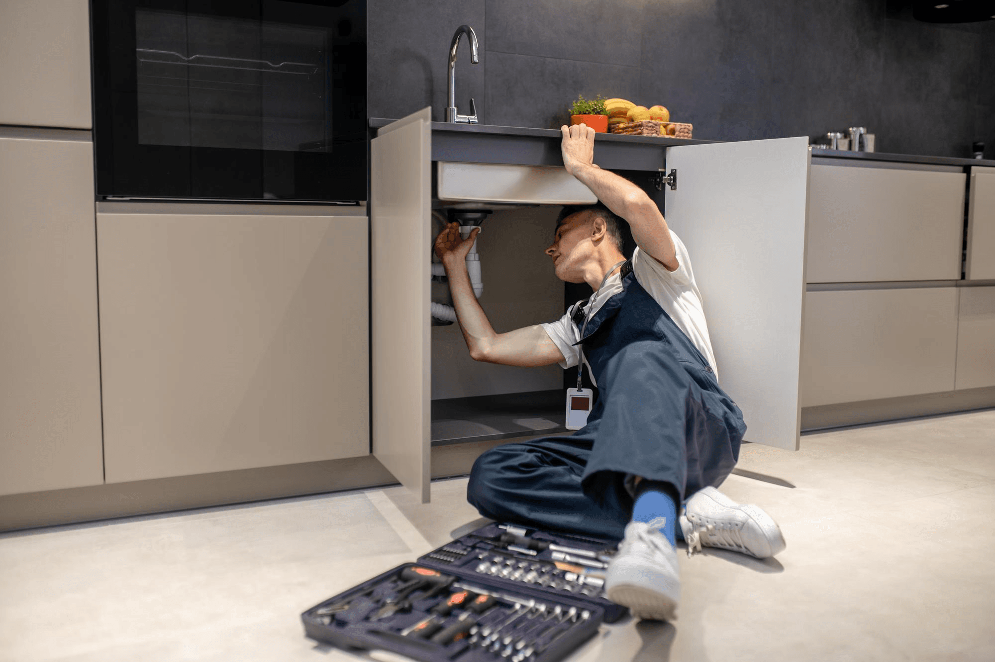 Handyman fixing plumbing under kitchen sink in Melbourne home